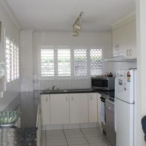a white kitchen with a sink and a refrigerator at 1 Aarons Villa in Noosaville