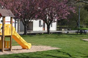 a playground with a yellow slide in a park at Gîte AU BORD DE L'EAU jusqu'à 8 personnes in Chambon-sur-Voueize