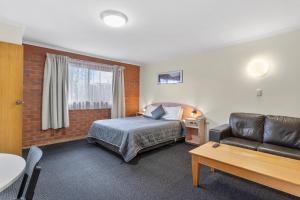 ein Hotelzimmer mit einem Bett und einem Sofa in der Unterkunft Martin Cash Motel in Hobart