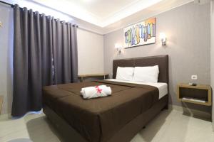 ein Schlafzimmer mit einem großen Bett mit einer braunen Tagesdecke in der Unterkunft Flamenco Urban Living in Jakarta