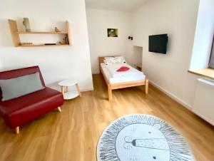 a room with a red chair and a bed and a rug at Gästehaus am Pfarrgarten in Mettlach