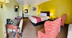 um quarto de hotel com uma cama, uma secretária e cadeiras em American Inn Princeton em Princeton