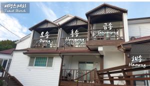 a house with a balcony with asian writing on it at Travel Sketch Pension in Geoje 