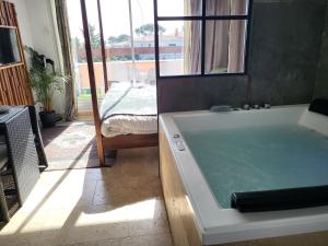 a bath tub sitting in a room with a window at "The Love Room Bandol" Jacuzzi & Vue Mer in Bandol