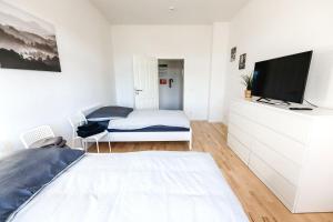 1 dormitorio blanco con 1 cama y TV en Modern & Chic Apartment with Balcony, en Gravenbruch
