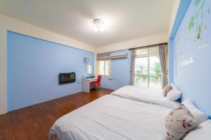 花蓮市的住宿－微加幸福民宿，一间卧室设有两张床和蓝色的墙壁