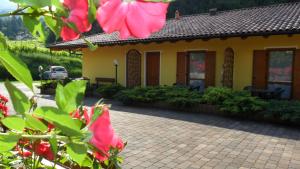 una casa gialla con fiori rossi davanti di Agriturismo La Decima a Trento