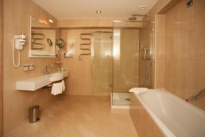 ein Bad mit einer Badewanne, einem Waschbecken und einer Dusche in der Unterkunft Monte Casa SPA & Wellness in Petrovac na Moru