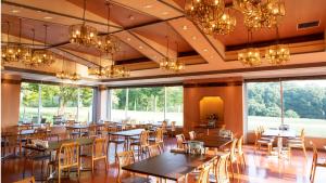 a dining room with tables and chairs and chandeliers at Kyukamura Taishakukyo in Shōbara