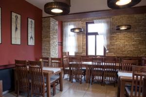 a restaurant with wooden tables and chairs and a brick wall at Penzion Marjána in Mníšek pod Brdy