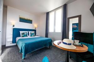 pokój hotelowy z łóżkiem i kapeluszem na stole w obiekcie La Villa Andry w mieście Ouistreham