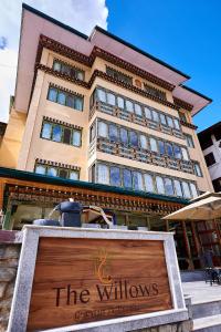um grande edifício com uma placa em frente em The Willows Hotel, Bhutan em Thimphu