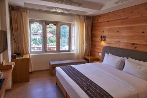 um quarto de hotel com uma cama e uma janela em The Willows Hotel, Bhutan em Thimphu