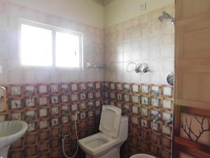 a bathroom with a toilet and a sink and a window at Cauvery Homestay in Somvārpet