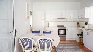 a white kitchen with a table and chairs at Blue Beach House in Caloundra