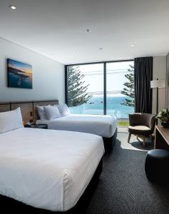 a hotel room with two beds and a large window at Sudima Kaikōura in Kaikoura