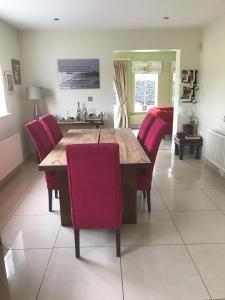 uma sala de jantar com uma mesa de madeira e cadeiras vermelhas em Burton Hall - Pauline em Carlow