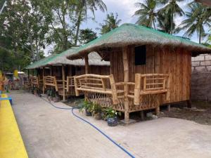 une petite cabane avec un toit en gazon et des chaises dans l'établissement Scott's Seaview Resort, à Idanao