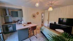 uma cozinha e sala de estar com uma mesa e um sofá em Appartement lumineux avec accès jardin et piscine chauffée em Avignon