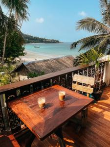 una mesa de madera en un balcón con vistas a la playa en Secret Place Hotel and Restaurant, en Haad Yao