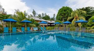 a swimming pool with blue chairs and umbrellas at Acajou Beach Resort in Baie Sainte Anne