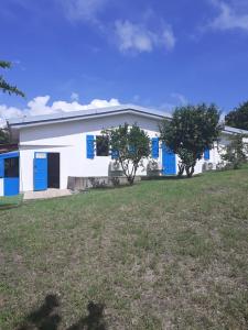 um edifício branco com portas azuis e um campo de relva em Grande villa climatisée,jardin, ideale famille, groupe amis, proche port de peche,littoral em Le Diamant