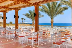 a restaurant with white tables and chairs and the ocean at Solymar Reef Marsa in Coraya Bay