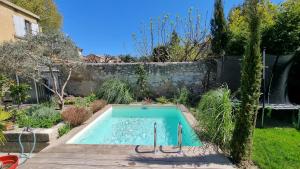 uma piscina num jardim com um deque de madeira em Appartement lumineux avec accès jardin et piscine chauffée em Avignon