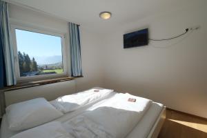 2 weiße Betten in einem Zimmer mit Fenster in der Unterkunft GO FOR MOUNTAINS Appartements in Eben im Pongau