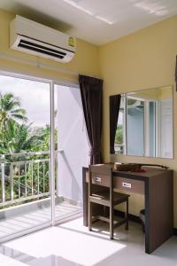 Cette chambre dispose d'un bureau et d'une fenêtre avec un balcon. dans l'établissement ตะวันอพาร์ทเม้นท์โฮเทลThawanapartmentHotel, à Satun