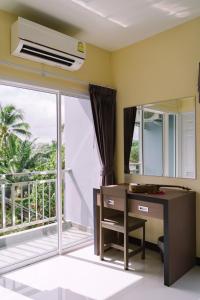 a room with a desk and a window with a balcony at ตะวันอพาร์ทเม้นท์โฮเทลThawanapartmentHotel in Satun +31 photos