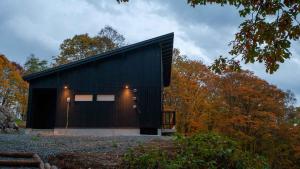a black house in the middle of a forest at Annupuri Chalets - Niseko in Niseko