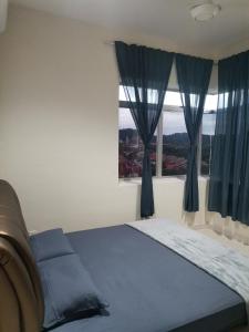 a bedroom with a bed with blue curtains and a window at Yuslina Homestay in Bandar Puncak Alam