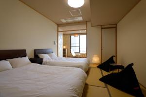 a hotel room with two beds and a window at 旅乃家 宇佐美温泉 海ホテル 本館ーアネックス館 in Ito