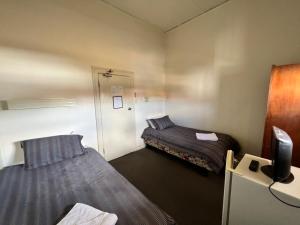 a small room with two beds and a tv at Black Lion Inn Hotel in Broken Hill