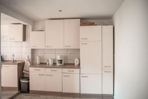 uma cozinha branca com armários e electrodomésticos brancos em Haus Morgentau mit Garten in zentraler Lage em Kassel