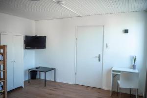 Zimmer mit einer weißen Wand, einem TV und einem Tisch in der Unterkunft Haus Morgentau mit Garten in zentraler Lage in Kassel