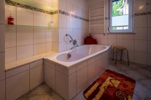 a white bathroom with a tub and a window at Ferienwohnung im Harz in Veckenstedt