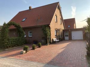 a house with a brick driveway and a white garage at Schoners Oog in Greetsiel