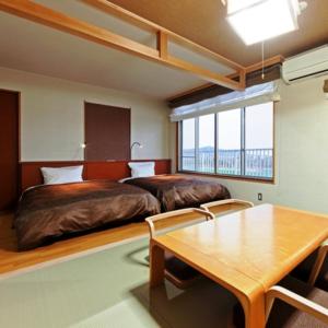 a bedroom with two beds and a table at Kyukamura Irago in Tahara