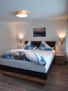 ニーダートハイにあるHaus Daheimのベッドルーム1室(青と白の枕が備わるベッド1台付)