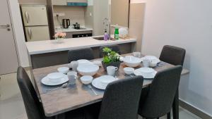 クアラルンプールにあるLuxury 5STAR 2Room Resort Suite Mid Valley Sunway Kuala Lumpur by Stayz Suitesのダイニングルームテーブル(椅子付)、白い食器が備わります。