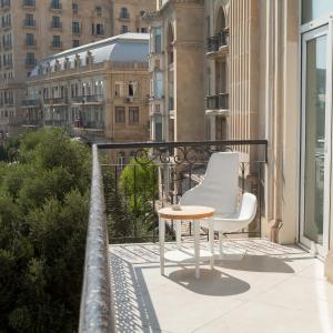 einen Balkon mit einem Tisch und 2 Stühlen auf einem Gebäude in der Unterkunft Promenade Hotel Baku in Baku