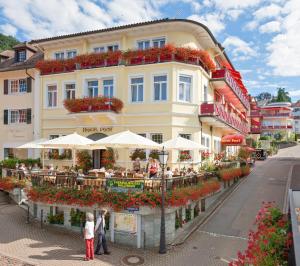 un edificio con mesas y sombrillas delante en Wellness Privathotel Post an der Therme, en Badenweiler