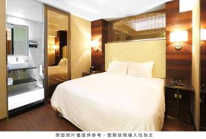 1 dormitorio con 1 cama blanca grande y baño en Royal Group Hotel Ho Yi Branch, en Kaohsiung