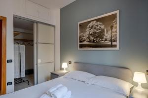Easylife - Classic and Comfy Porta Romana Flat في ميلانو: غرفة نوم بسرير ابيض وصورة على الحائط