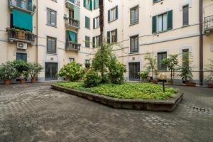 un patio en un edificio con un árbol en el medio en Easylife - Classic and Comfy Porta Romana Flat, en Milán
