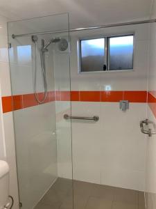 a bathroom with a glass shower with a window at Jetty Road Granny Flat in Normanville