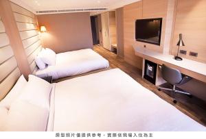 a hotel room with two beds and a television at Royal Group Hotel Minghua Branch in Kaohsiung