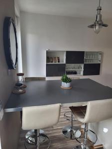 a kitchen with a black counter and two white chairs at Très bel appartement cosy en hyper centre in Romorantin